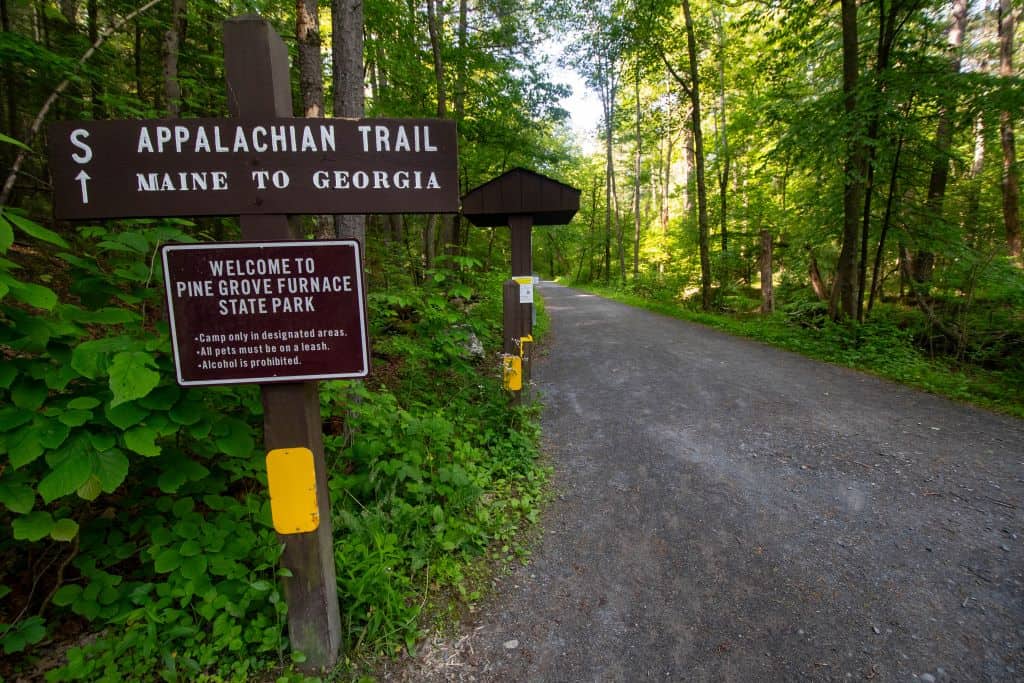 The Appalachian Trail wooden sign welcomes hikers to Pine Grove Furnace State Park and directs them along the trail.