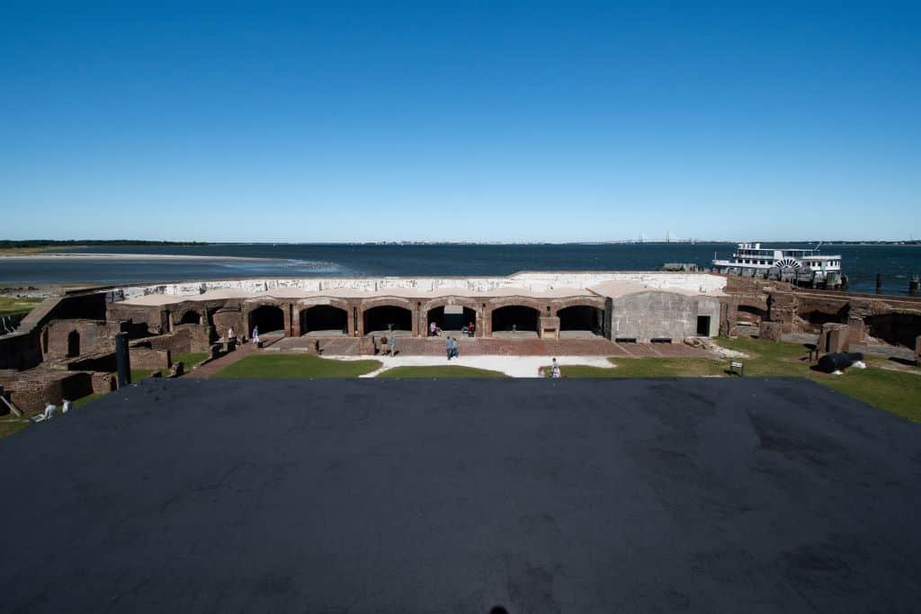 A view of the Charleston Harbor from the top of the Battery Huger includes the brick arches of the fort below with the ferry in the background and to the right.