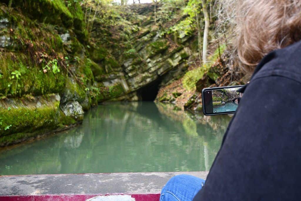 A woman holds her smartphone camera ready as she approaches the entrance to Penn's Cave