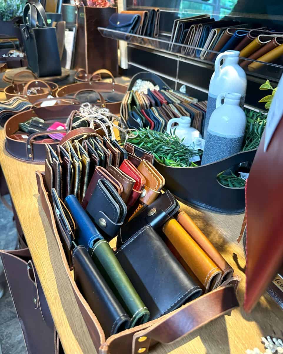 A display of handcrafted leather goods, including wallets, key holders, and tote bags, at an Amish cottage shop in Shipshewana, Indiana. The shop showcases high-quality leather craftsmanship, making it a must-visit for those looking for authentic Amish-made goods.