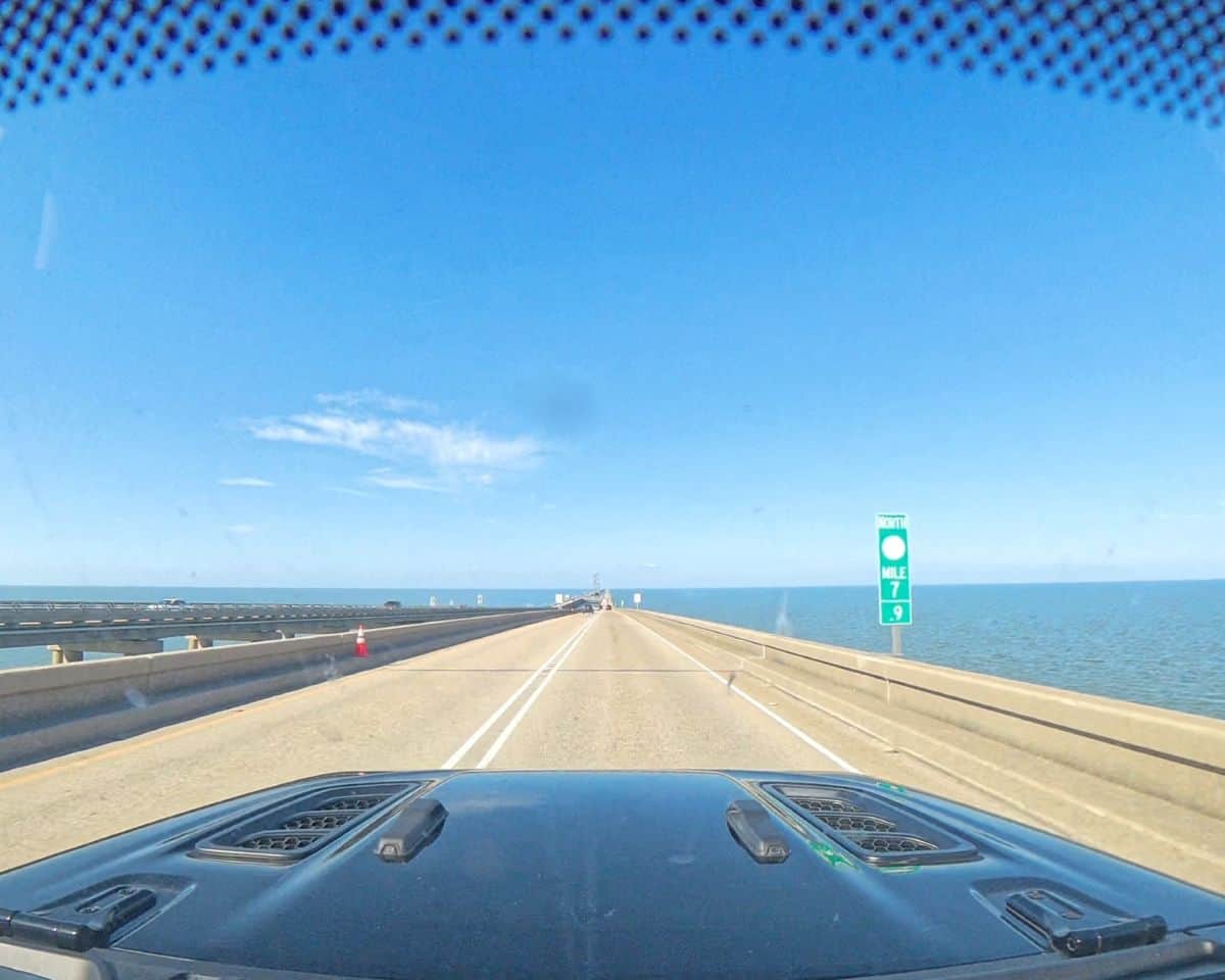 View from inside a vehicle driving across the Lake Pontchartrain Causeway with water stretching to the horizon on both sides of the long bridge. The scene captures the iconic drive across one of the longest bridges over water on Louisiana’s Northshore route.