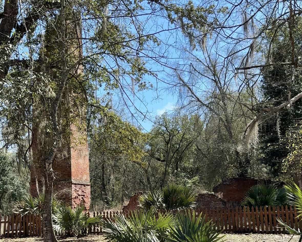 Brick ruins of a historic sugar mill chimney rise among palmetto plants and trees draped in Spanish moss at Fontainebleau State Park. The preserved structure reflects the site’s history as a 19th century sugar plantation on Louisiana’s Northshore.