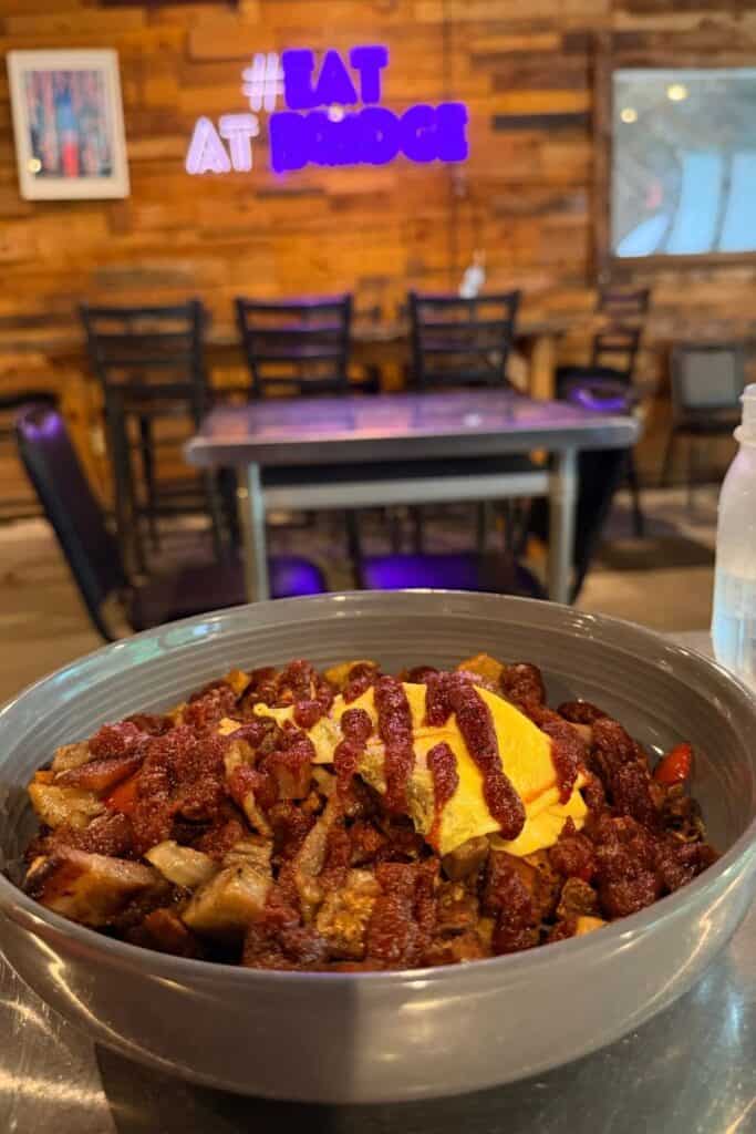 A breakfast bowl topped with eggs, potatoes, vegetables, meat, and sauce inside Bridge Cafe & Bistro in Hurricane, West Virginia.